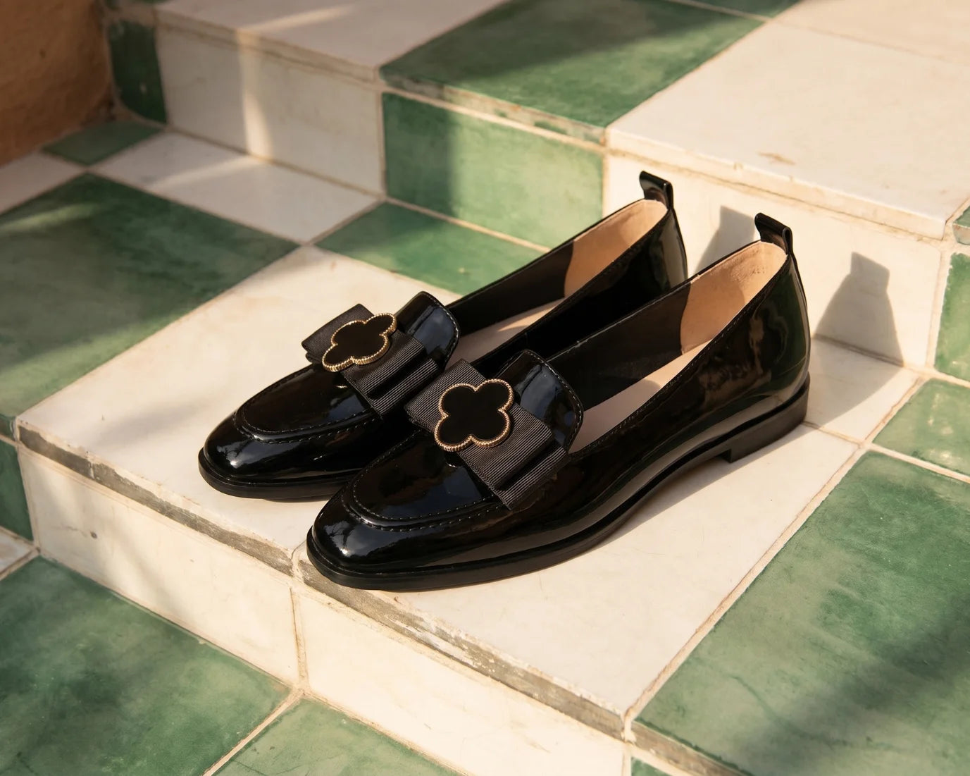 Dark green patent leather Morbido ladies pump with a decorative bow and silver buckle detail, viewed from the side.