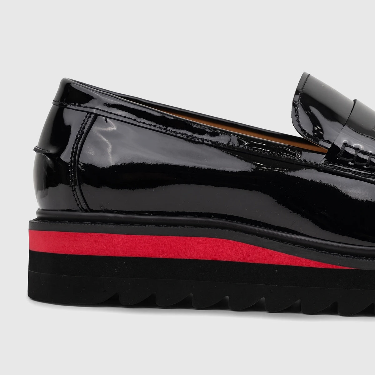 Babucci men's black patent leather slip-on loafer with a chunky red and black lug sole, shown in a close-up side view.