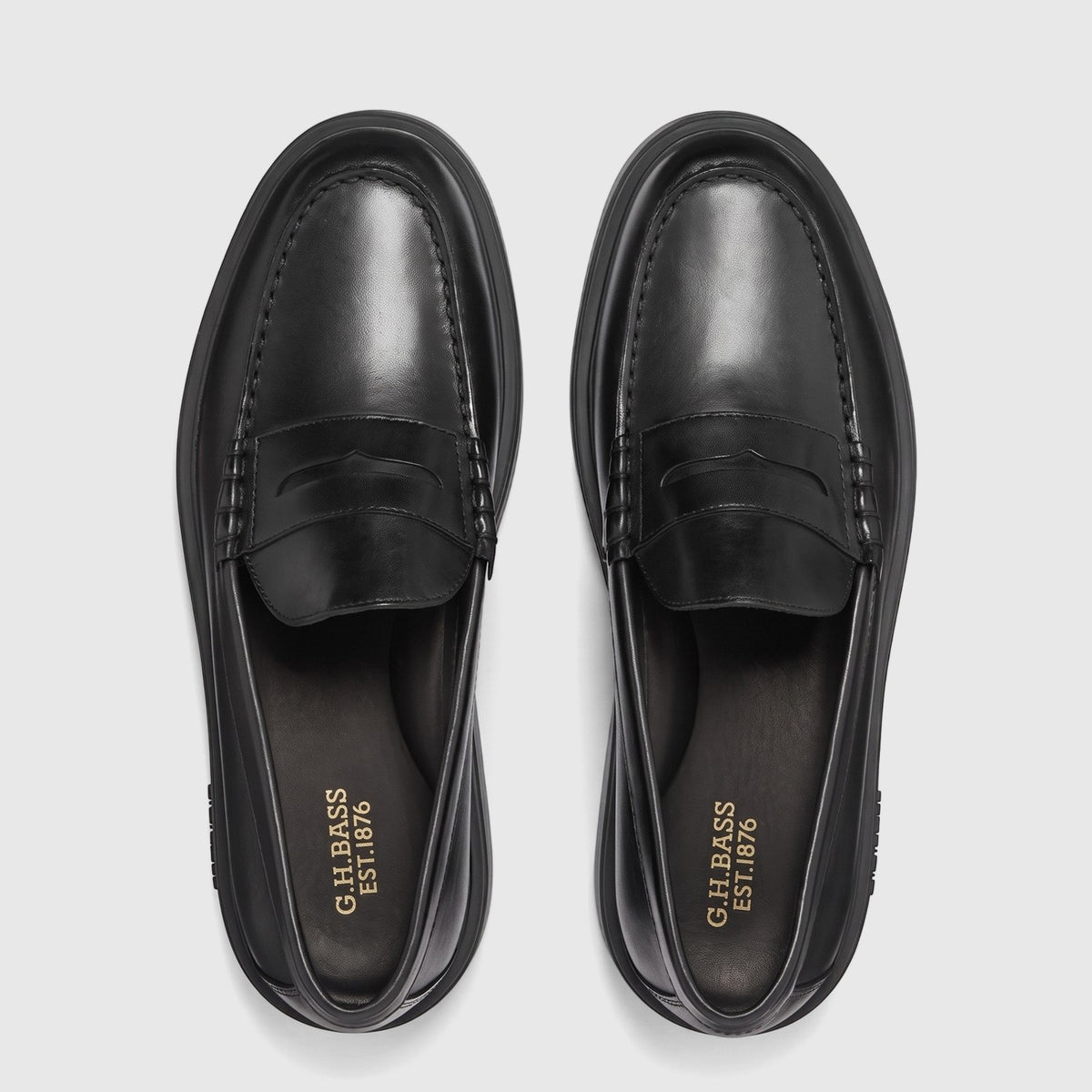 Overhead view of a pair of black leather Bass Men's Bosco Cup Loafers with penny strap detail and thick soles.