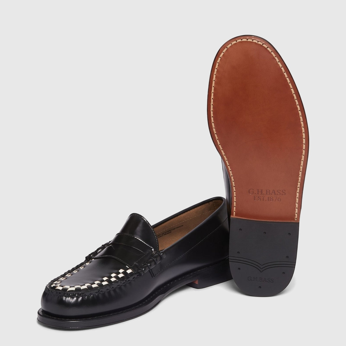 Black leather men's Bass Larson Weave penny loafers with white and black woven vamp detail, one shoe displaying its brown