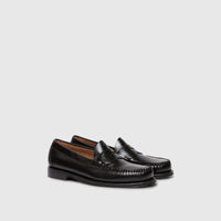 A pair of black leather Bass Weejun Logan penny loafers, viewed from a slightly elevated side angle, showcasing their