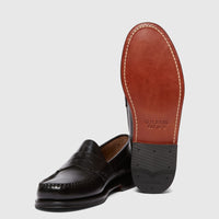 Pair of black leather Bass Men's Weejun Logan Penny Loafers, one shown upright and the other displaying its brown and black