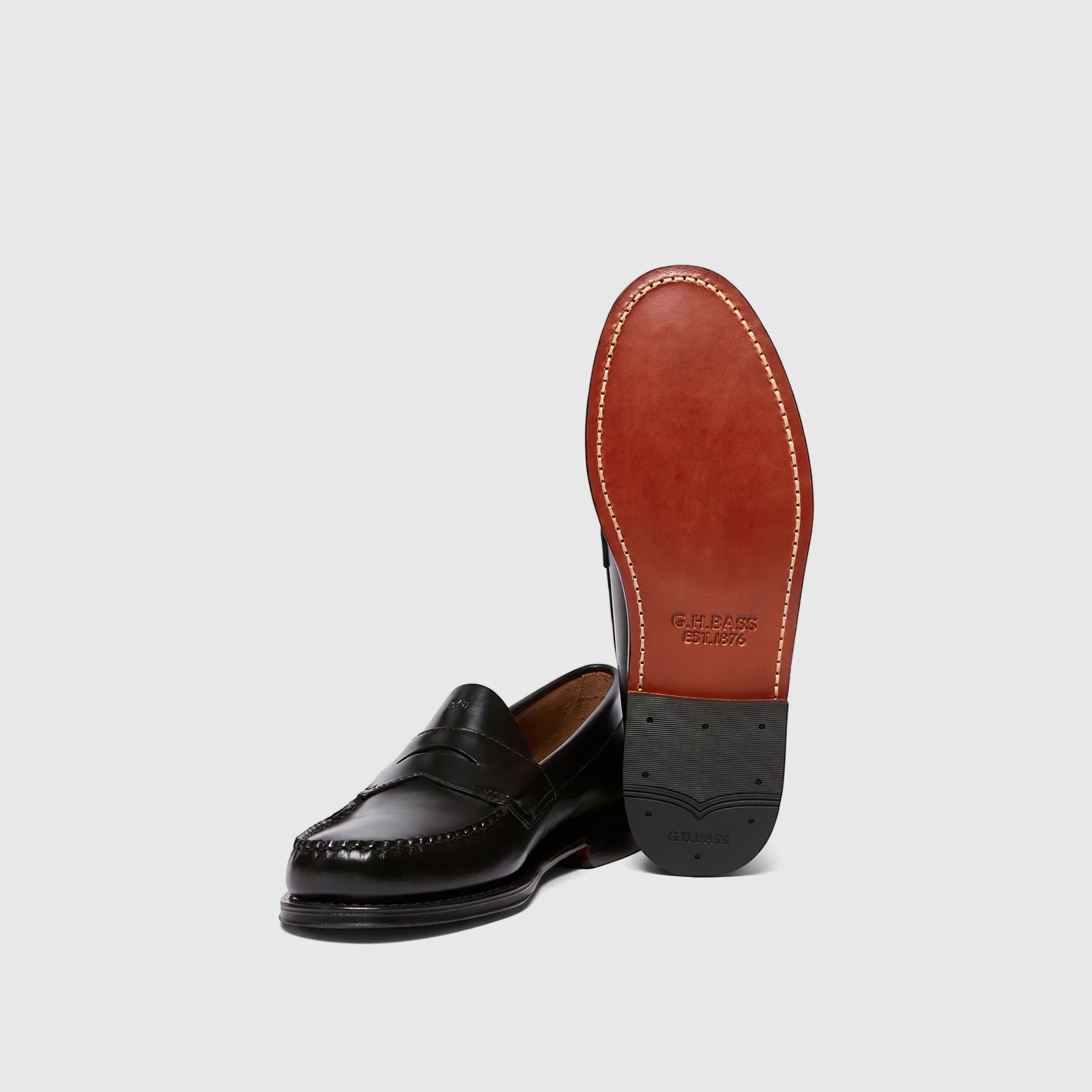 Black leather men's penny loafers from G.H. Bass, showing the top and a full view of the distinctive stitched sole.