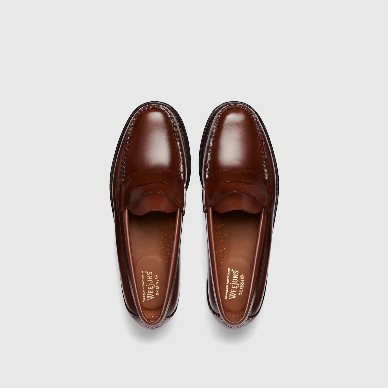 Pair of Bass Men's Weejun Logan penny loafers in brown leather, presented in an overhead studio shot.
