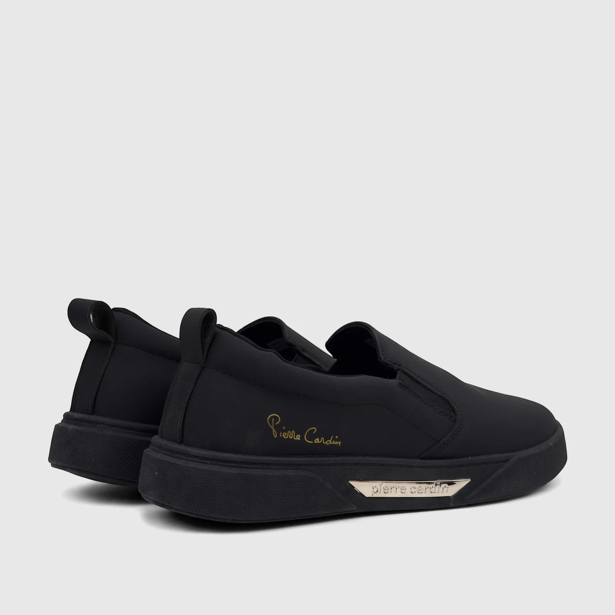 Pair of black PC Ladies Casual Slip On Sneakers, featuring gold script branding and silver sole plaque, side view.
