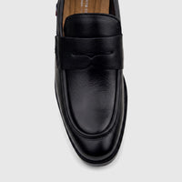 Black youth slip-on loafer dress shoe, with a penny strap design, made from faux leather, viewed from an overhead angle.