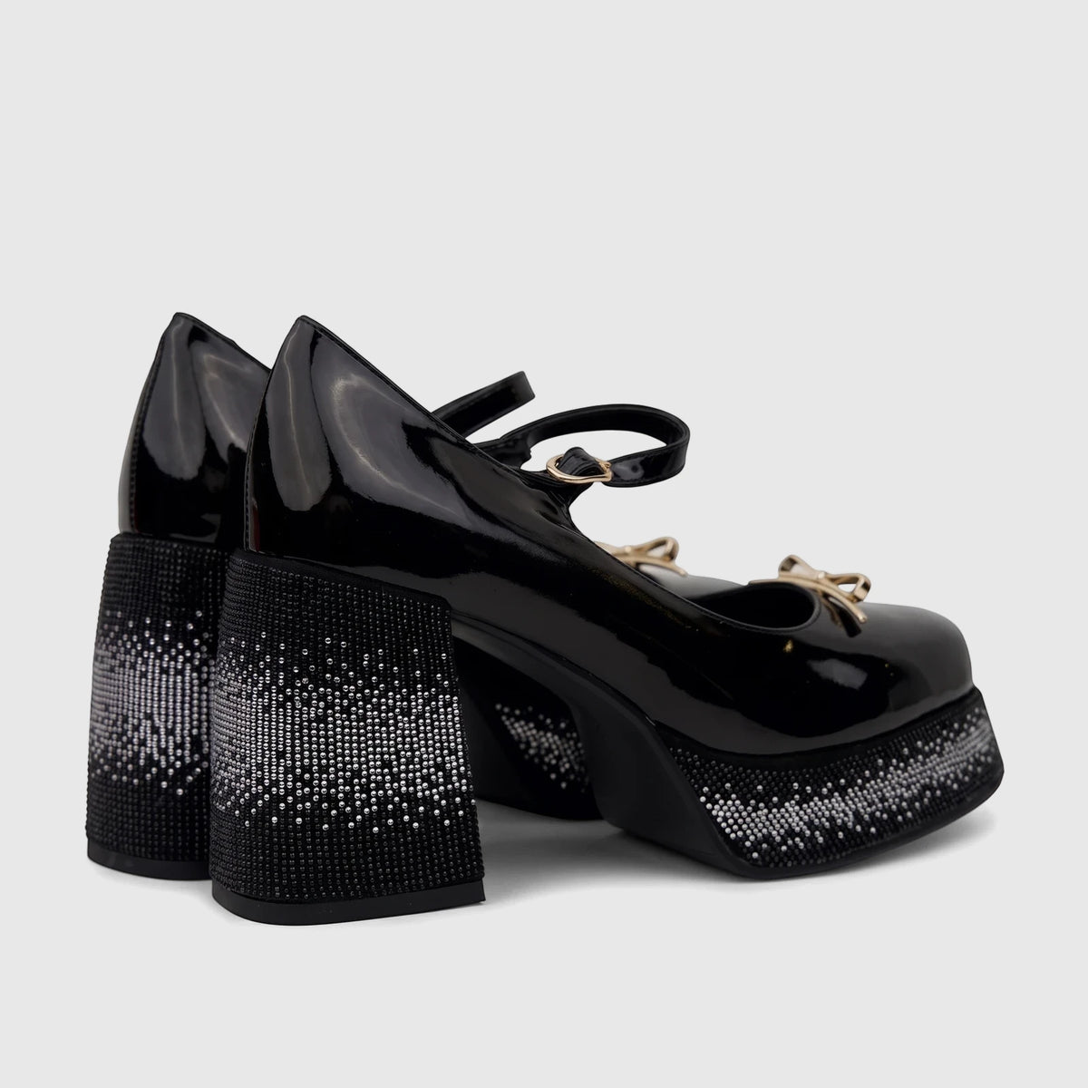 Black patent leather Mary Jane platform shoes with rhinestone-covered block heels and platforms, featuring gold bow accents.