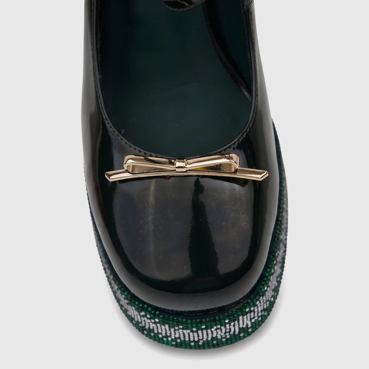 Close-up of a dark green patent leather Bulbul Ladies Block Heel Mary Jane shoe, with a gold bow and green and white bling