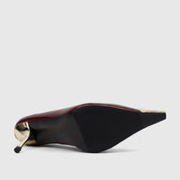 Burgundy patent leather dress court shoe with a pointed toe and gold stiletto heel, photographed from a bottom-side view