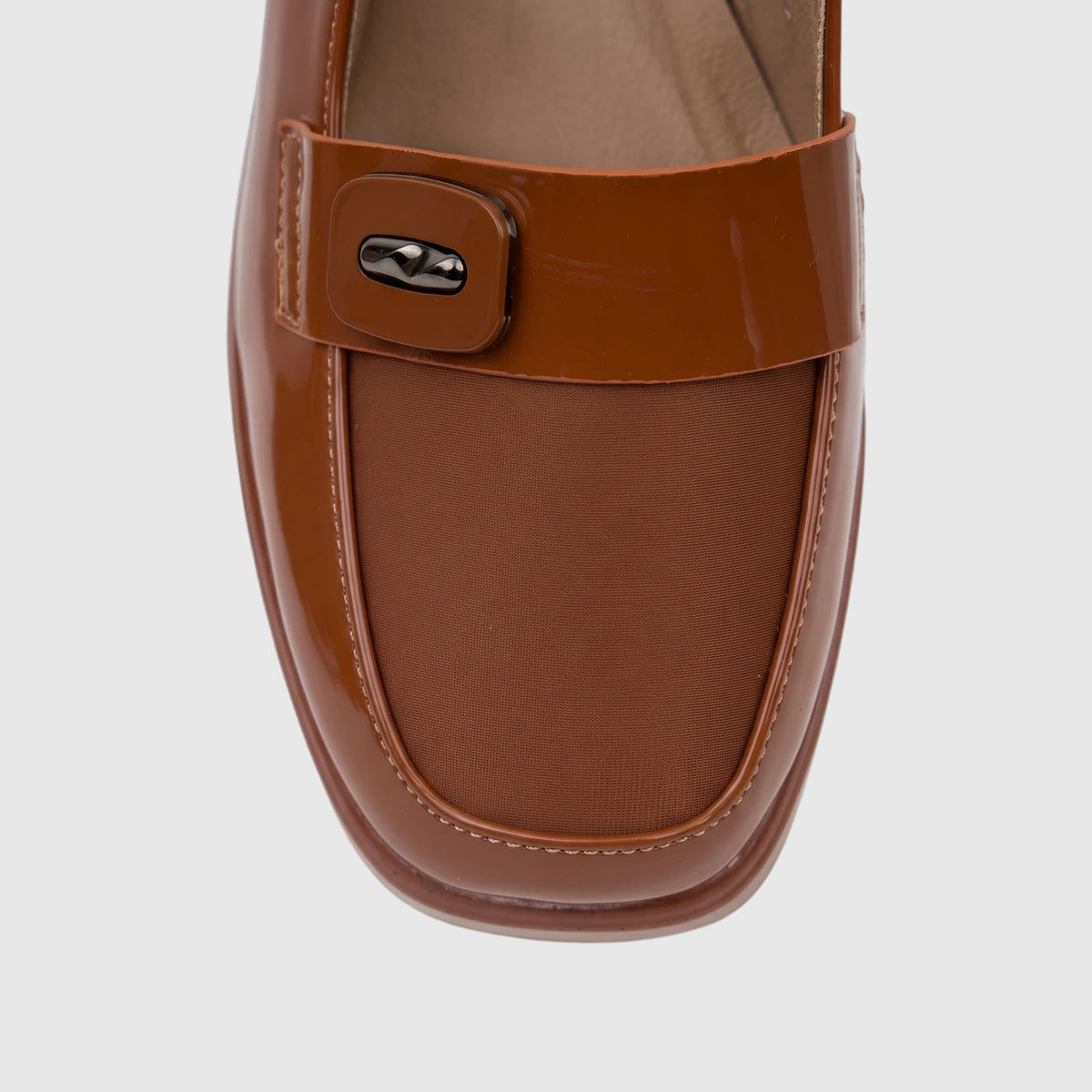 Close-up of a women's camel brown patent leather block heel sandal, featuring a decorative buckle and woven fabric detail.