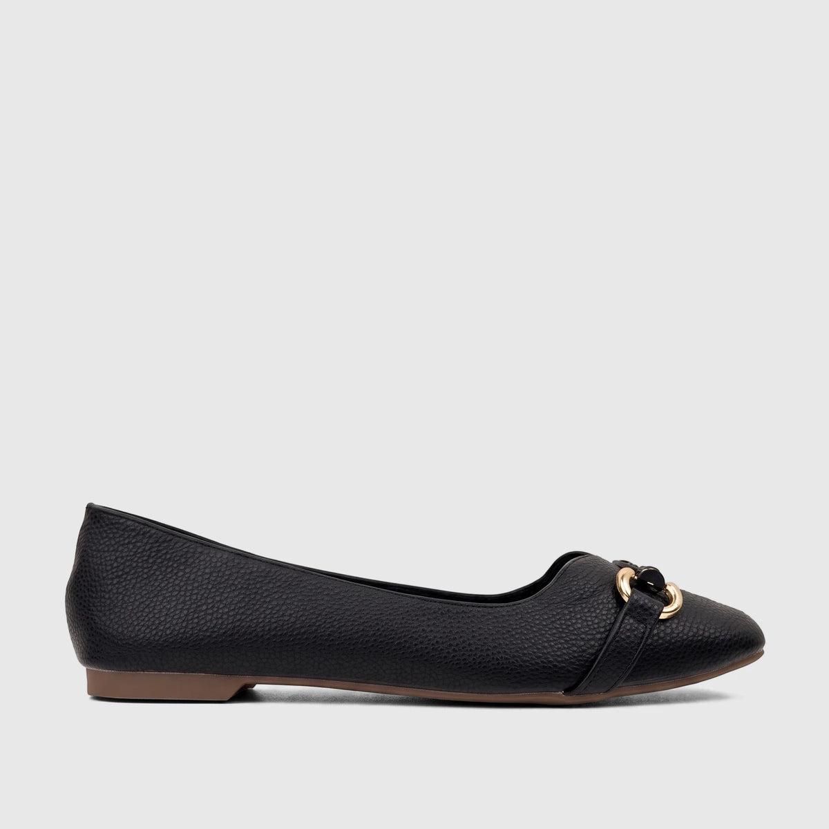 Side view of a single Bulbul Ladies Casual Pump in black textured faux leather with a prominent gold-tone buckle accent on