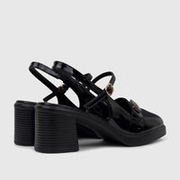 Angled view of black patent leather Bulbul ladies dress block heel sandals with gold buckles and ribbed heels.