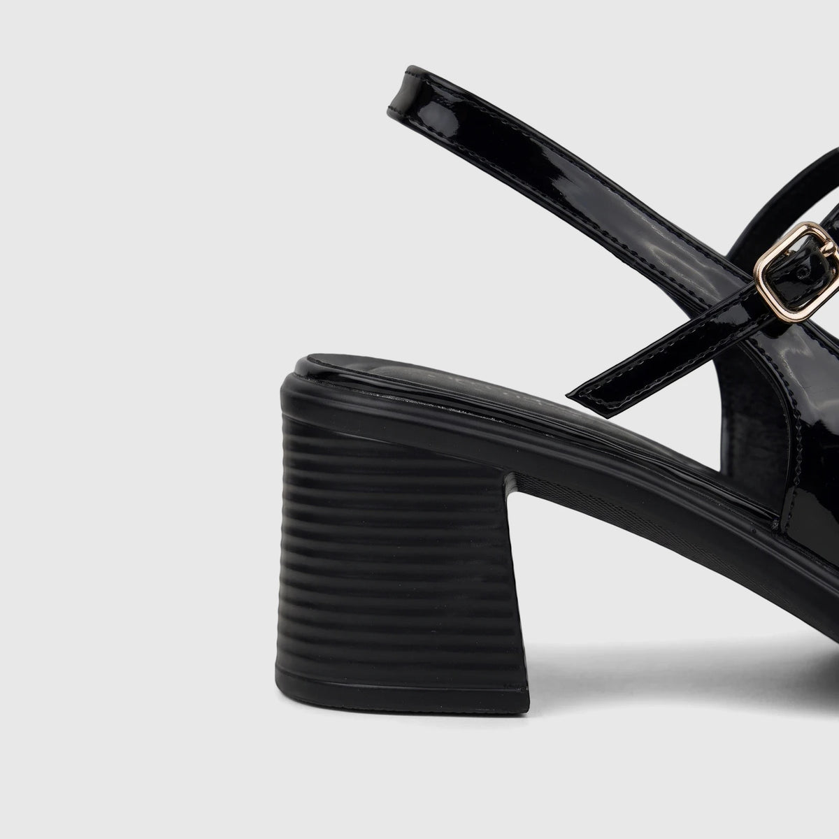 Black patent leather block heel sandal for ladies, featuring a glossy finish, gold-tone buckle, and sturdy heel.