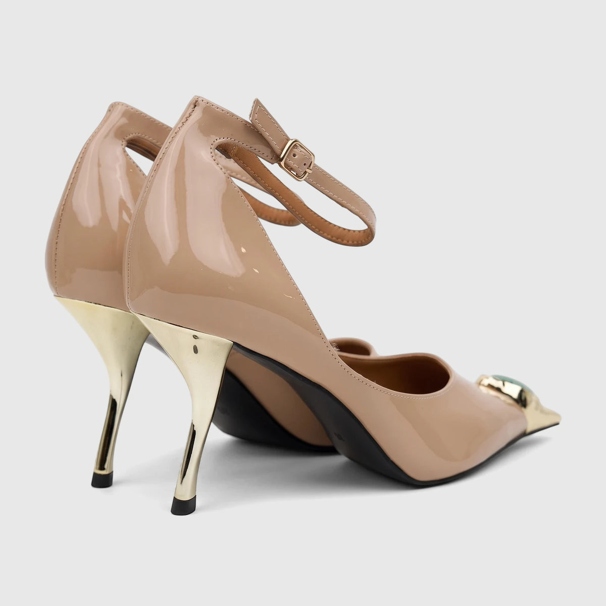 Elegant beige patent leather dress court shoes with an ankle strap, pointed toe, unique gold stiletto heels, and a green