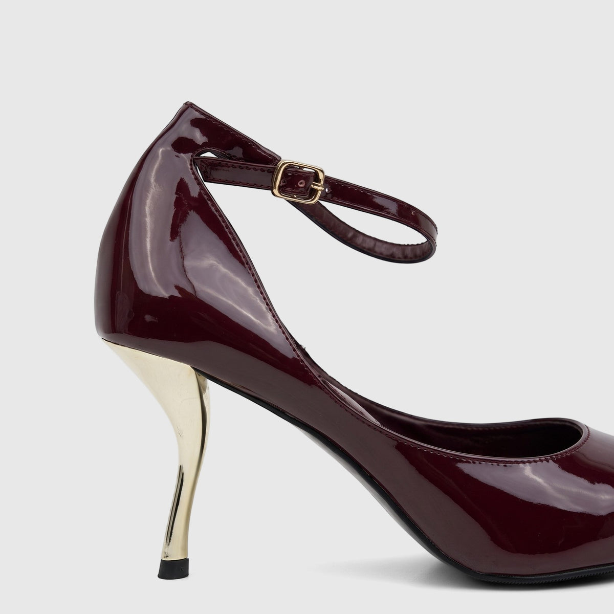 Purple patent leather high-heel court shoe with a sculpted gold heel and an ankle strap, shown in a side view.