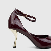 Purple patent leather high-heel court shoe with a sculpted gold heel and an ankle strap, shown in a side view.