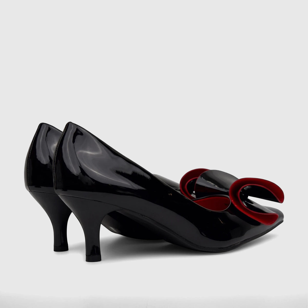 A pair of shiny black patent leather Bulbul Ladies Dress Court Shoes with elegant red bow details and kitten heels, viewed