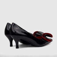 A pair of shiny black patent leather Bulbul Ladies Dress Court Shoes with elegant red bow details and kitten heels, viewed