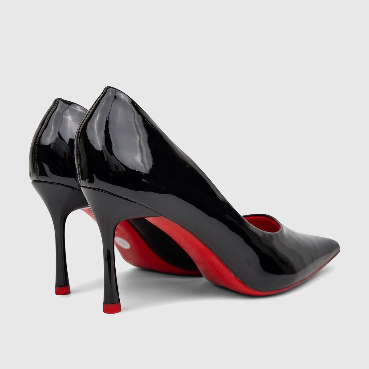 Bulbul black patent leather high-heel dress court shoes with pointed toes and iconic red soles, viewed from a side-rear
