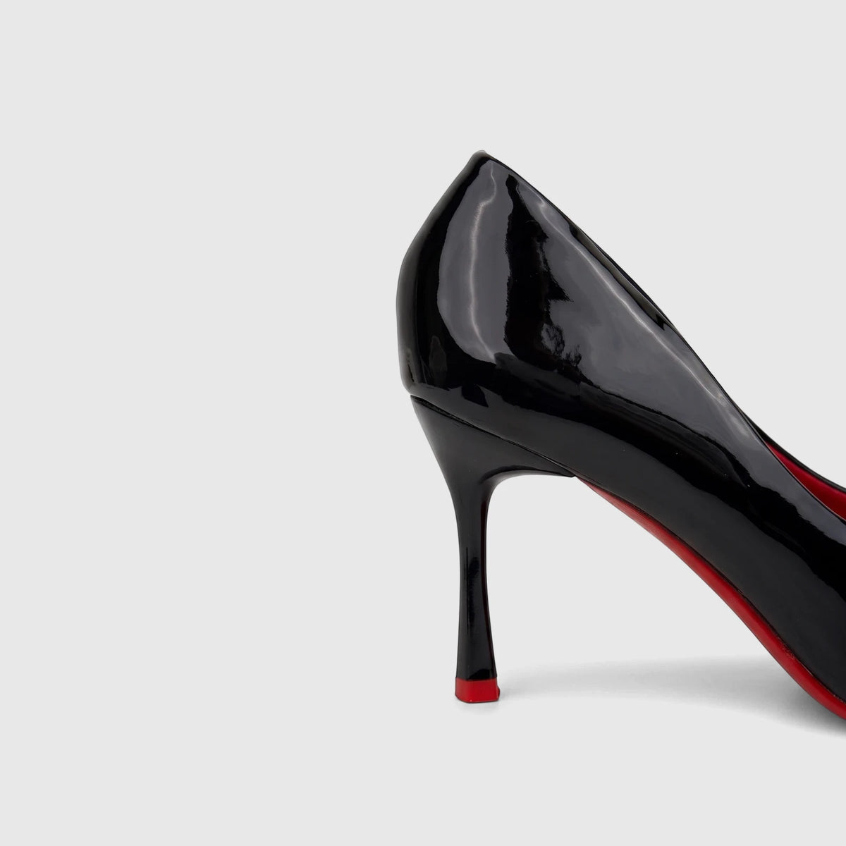 Close-up of a black patent leather Bulbul Ladies Dress Court Shoe with a high heel and distinct red sole.