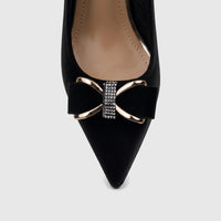 A close-up of a black Bulbul Ladies Dress Court Shoe with a pointed toe and a decorative bow featuring gold-tone hardware