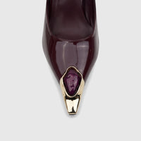 Close-up of a Bulbul purple patent leather pointed-toe court shoe with a gold toe cap and purple jeweled embellishment.