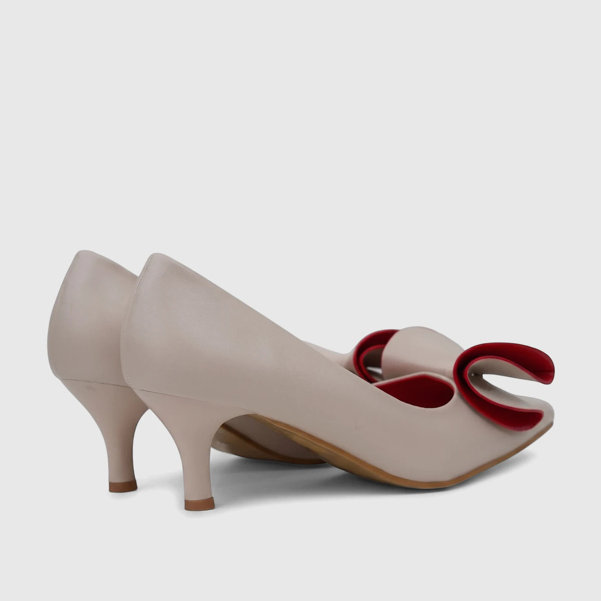 A pair of elegant Bulbul Ladies Dress Court Shoes in beige, featuring a striking red bow on the vamp and a stylish kitten