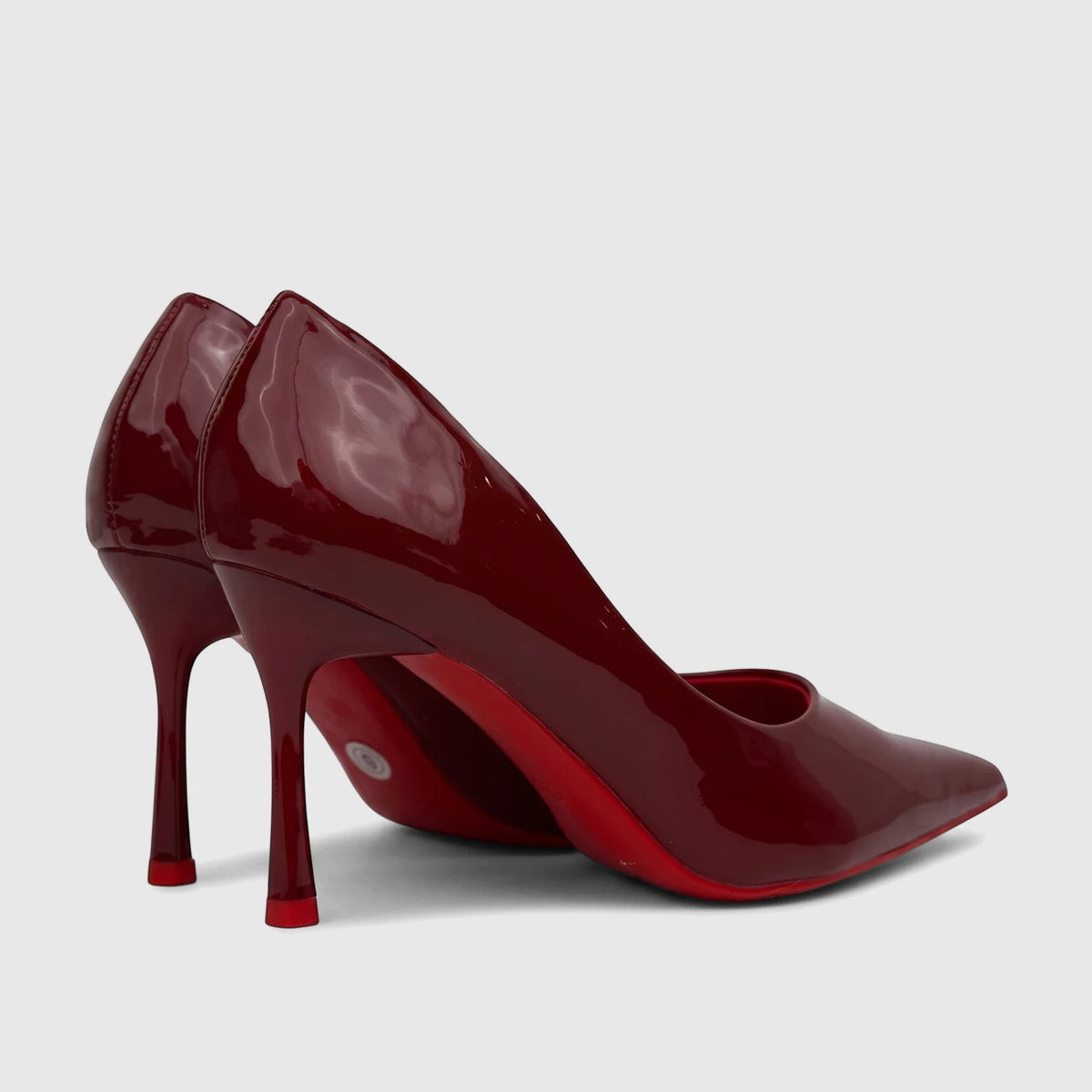 Pair of glossy red patent leather Bulbul ladies dress court shoes with stiletto heels and distinctive red soles.