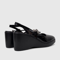 A pair of black patent leather Bulbul Ladies Dress wedge heel sandals with slingback straps, positioned at a side-back view.