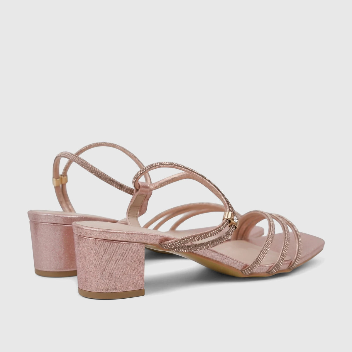 Pink glitter block heel sandals with thin sparkly straps and a square toe, seen from a slightly elevated side angle.