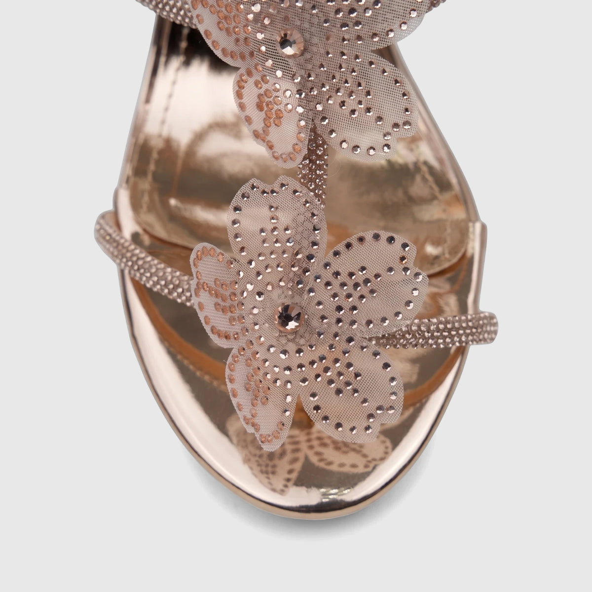 Rose gold high heel sandal with shimmering rhinestone flower embellishments and metallic finish, viewed from above.