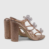 Pair of rose gold block heel sandals with rhinestone-embellished straps and clear floral details on a white background.