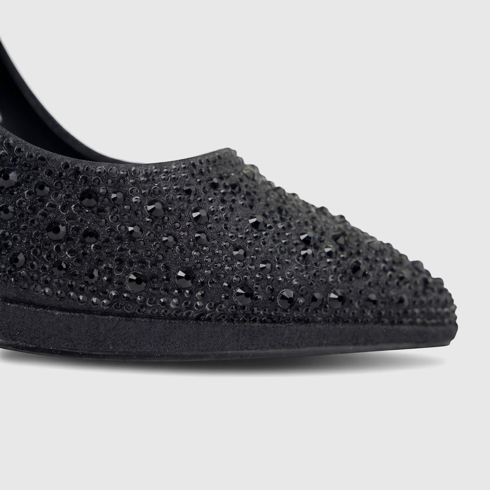 Close-up of a black high-heeled evening court shoe, adorned with sparkling black studs, shown on a white background.
