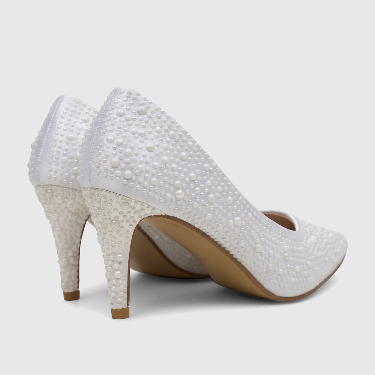 Pair of white pearl-embellished high-heeled court shoes on a light background, viewed from the back.
