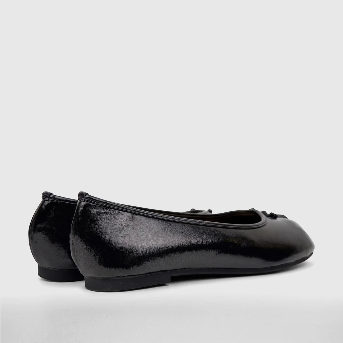 Pair of black patent leather Bulbul Ladies Evening Pumps, side view, featuring small decorative bows.