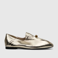 A women's flat loafer-style evening pump in shiny light gold metallic finish, featuring a pointed toe and subtle hardware