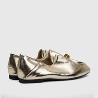 Pair of light gold metallic Bulbul Ladies Evening Pump flats with a pointed toe and black sole, viewed from the side.
