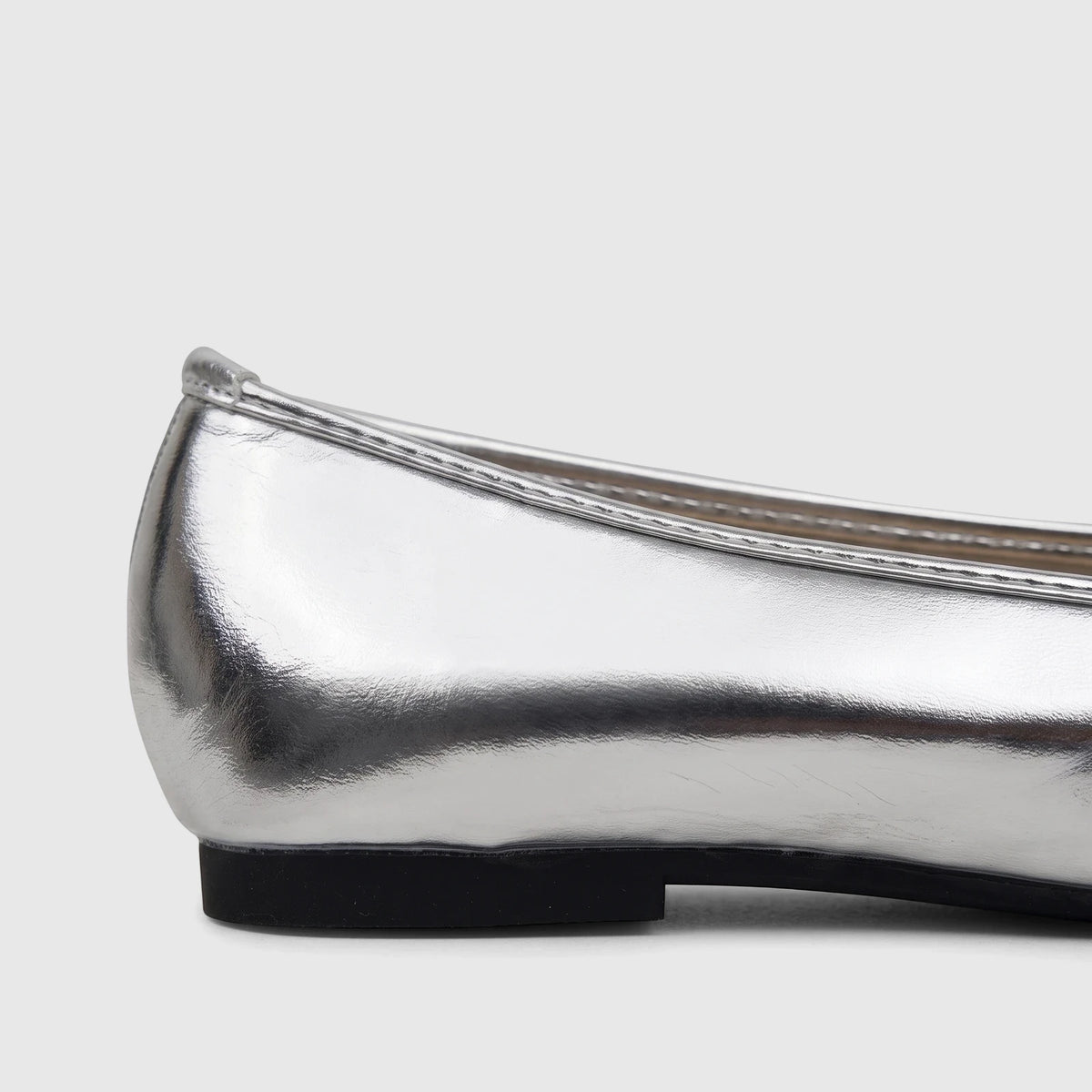 Side view of a Bulbul ladies' evening pump in shimmering silver metallic, featuring a sleek design and a contrasting black