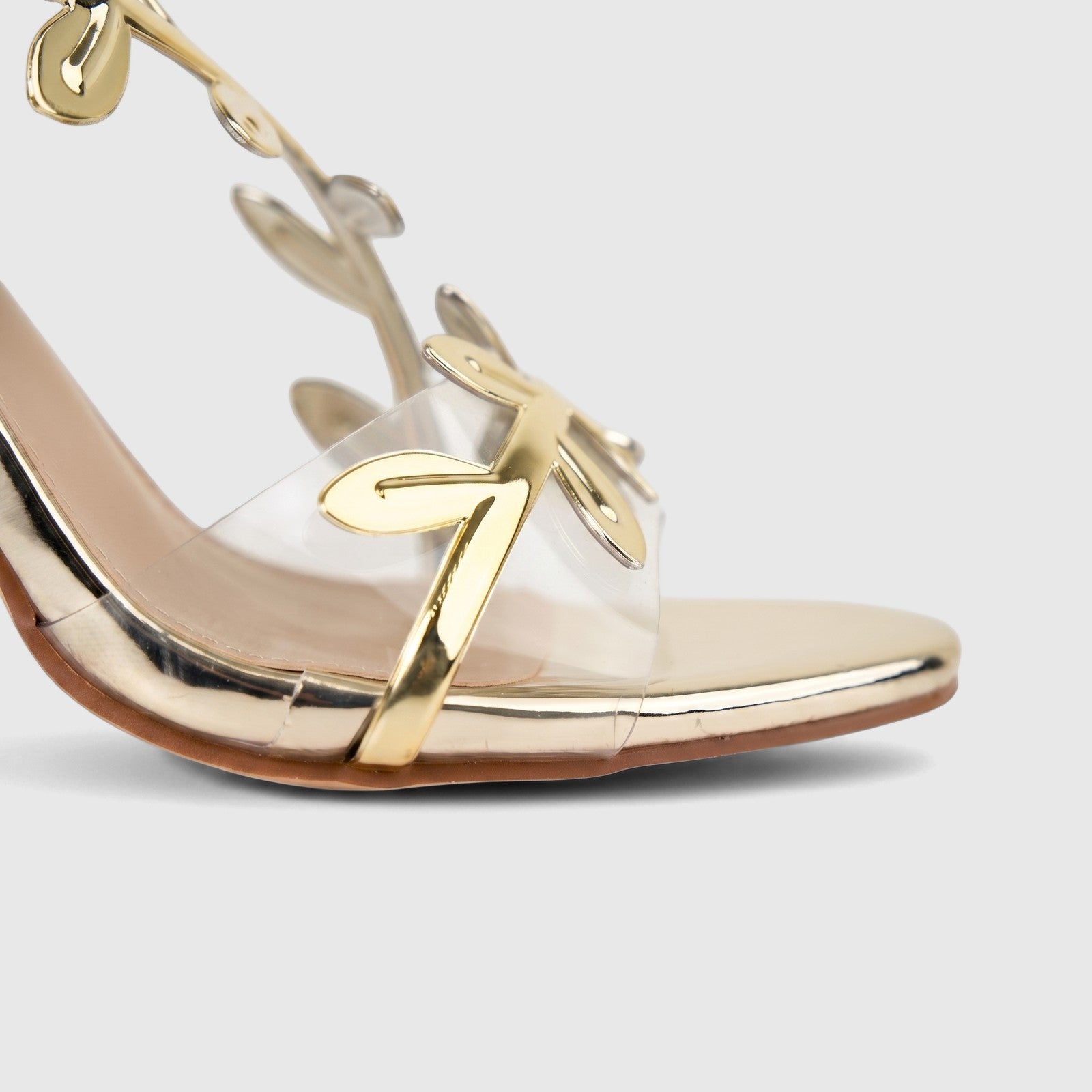 Bulbul Ladies Evening Sandal in metallic gold with clear straps and intricate leaf-shaped embellishments, high heel.