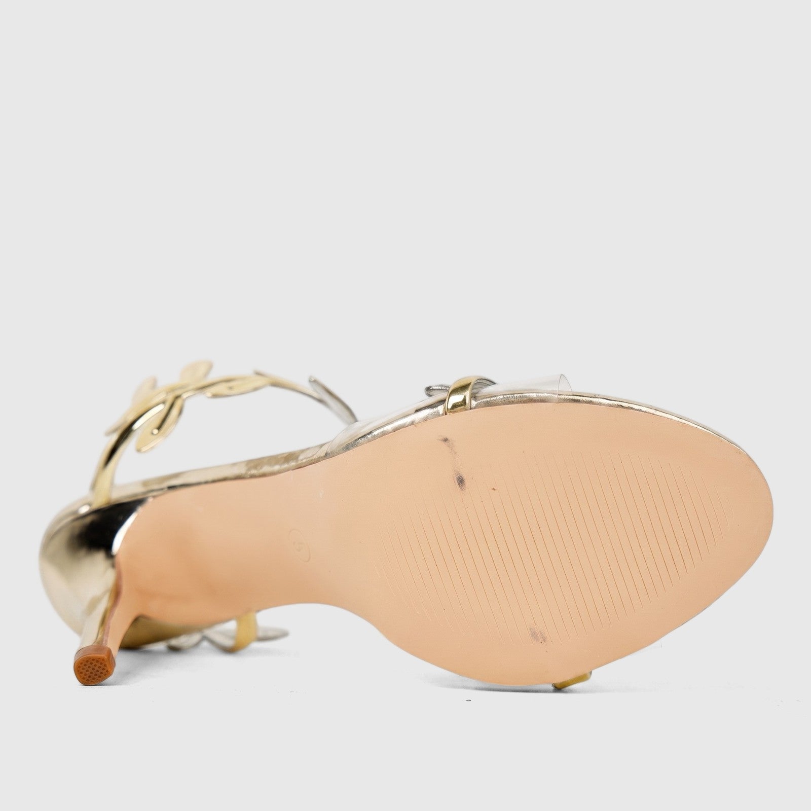 Bulbul Ladies Evening Sandal in gold metallic, viewed from the bottom revealing the textured beige sole and clear straps
