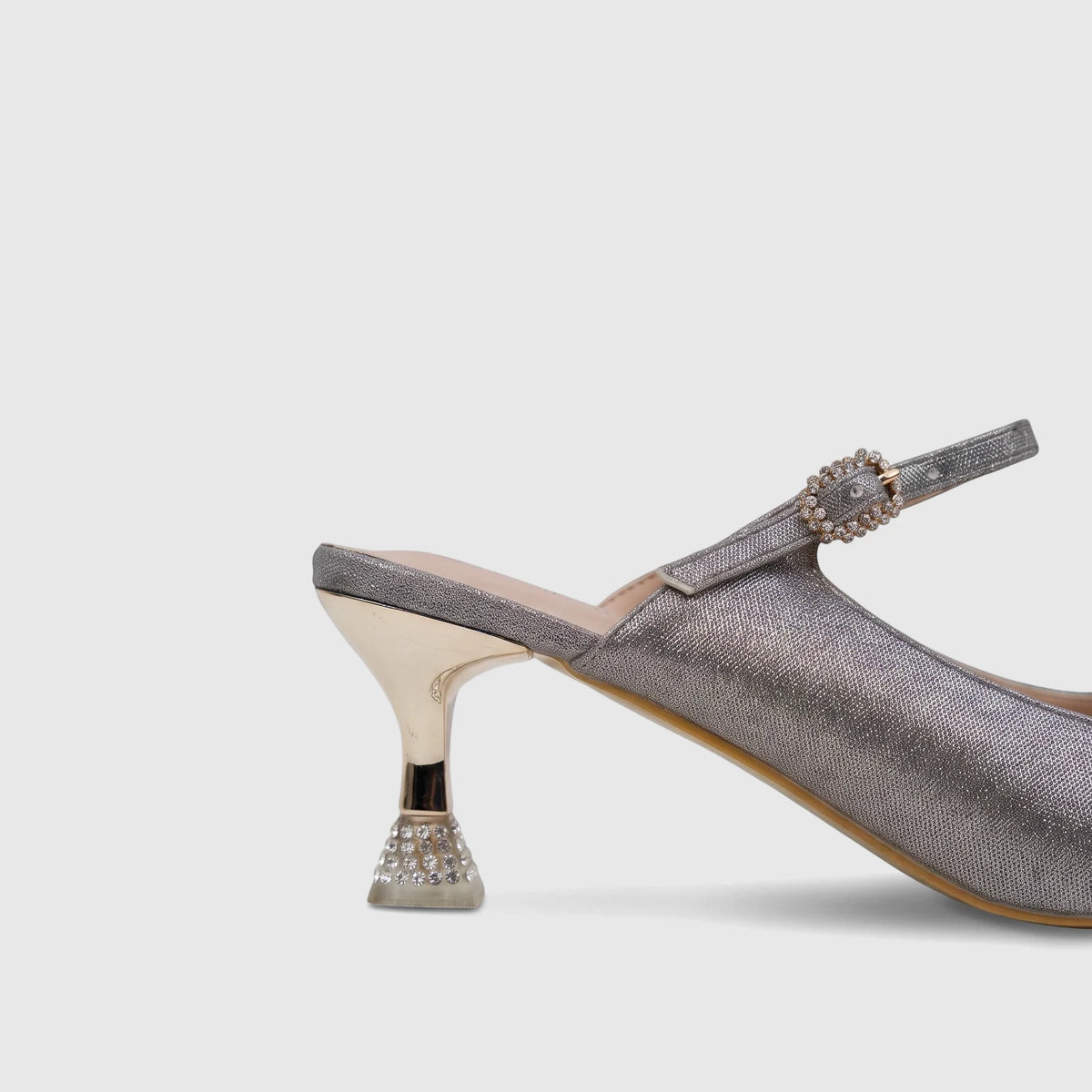 Close-up of a silver glitter Bulbul slingback kitten heel with a gold heel and rhinestone buckle.