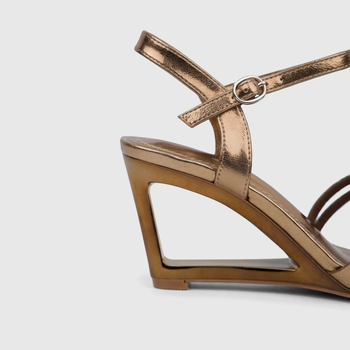 Bronze metallic slingback wedge sandal for ladies, featuring a unique cutout heel design and an adjustable ankle strap.