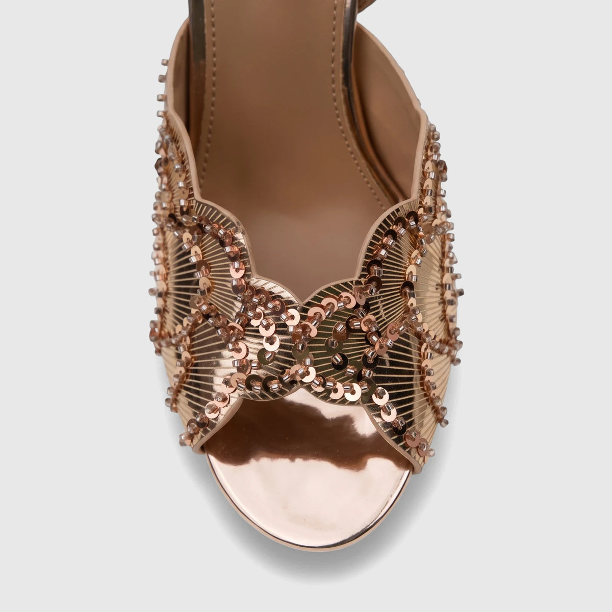 Close-up of a rose gold sequined slingback sandal with a metallic open toe, designed for evening wear, from a front view.