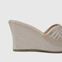 Close-up side view of a women's light gold wedge sandal with glitter detailing and rhinestone-embellished transparent mesh