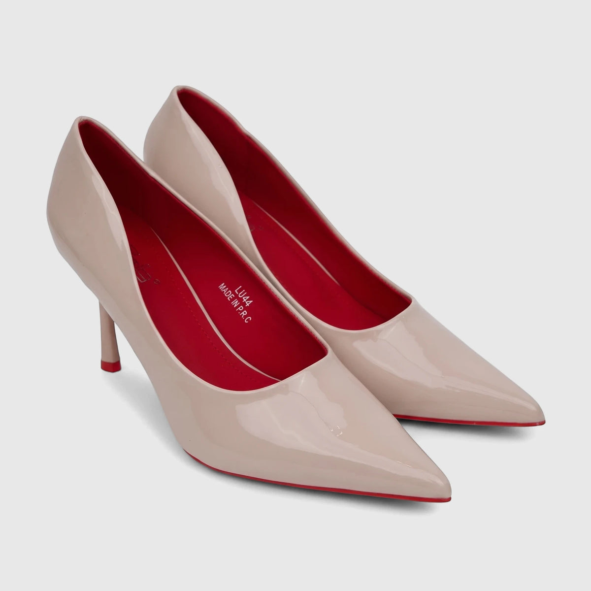 Nude patent leather pointed-toe high heel court shoes with bright red insoles and heel tips, shown angled on a light surface.