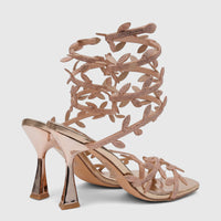 Rose gold high heel sandals with ornate spiral ankle straps and leaf-motif rhinestones. Elegant evening footwear.