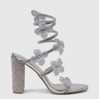 Bulbul Ladies silver spiral strap evening heel sandal with rhinestone-covered block heel and floral embellishments.