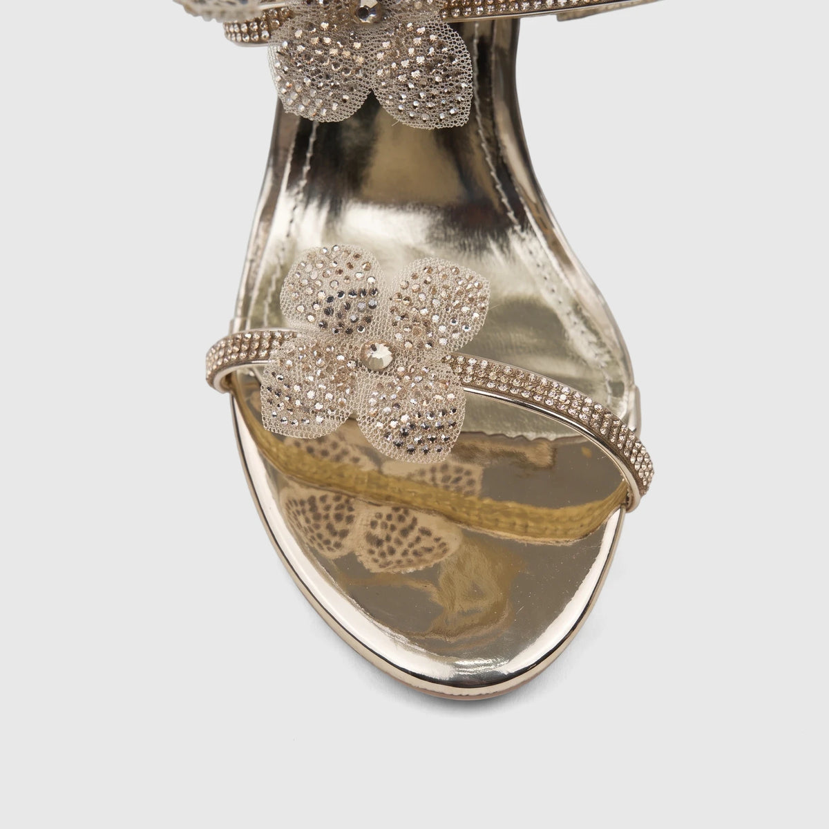 Close-up of a shimmering gold Bulbul Ladies Spiral Strap Evening Heel Sandal adorned with crystal flowers.