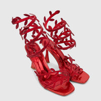 A pair of shiny red Bulbul Ladies Spiral Strap Evening Heel Sandals with rhinestone-embellished leaf details, perfect for