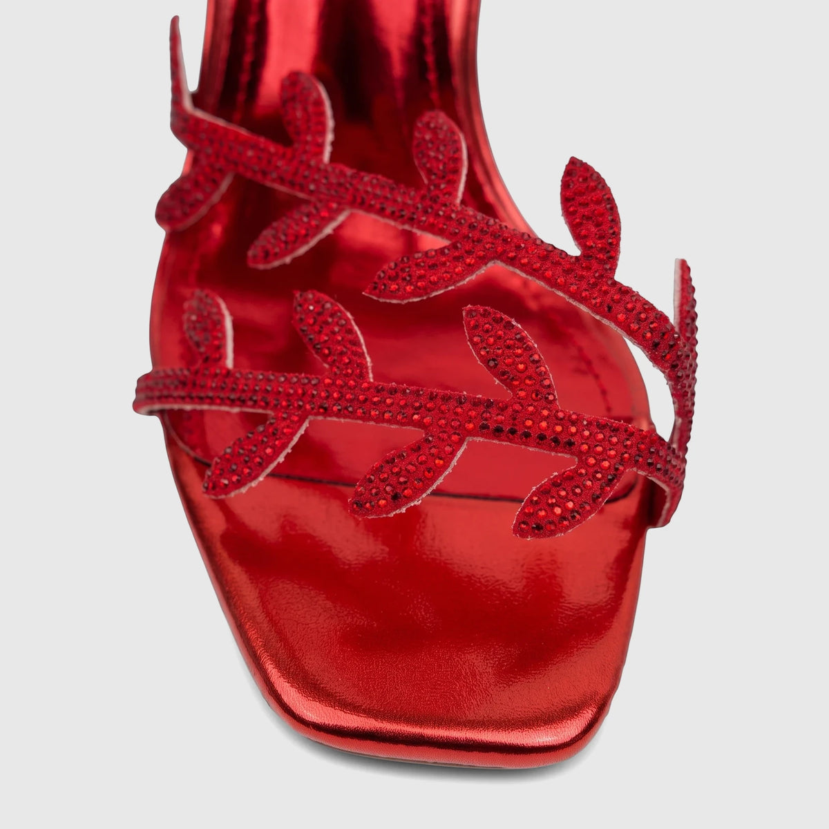 Close-up of a vibrant red metallic Bulbul Ladies Spiral Strap Evening Heel Sandal, adorned with intricate red rhinestone
